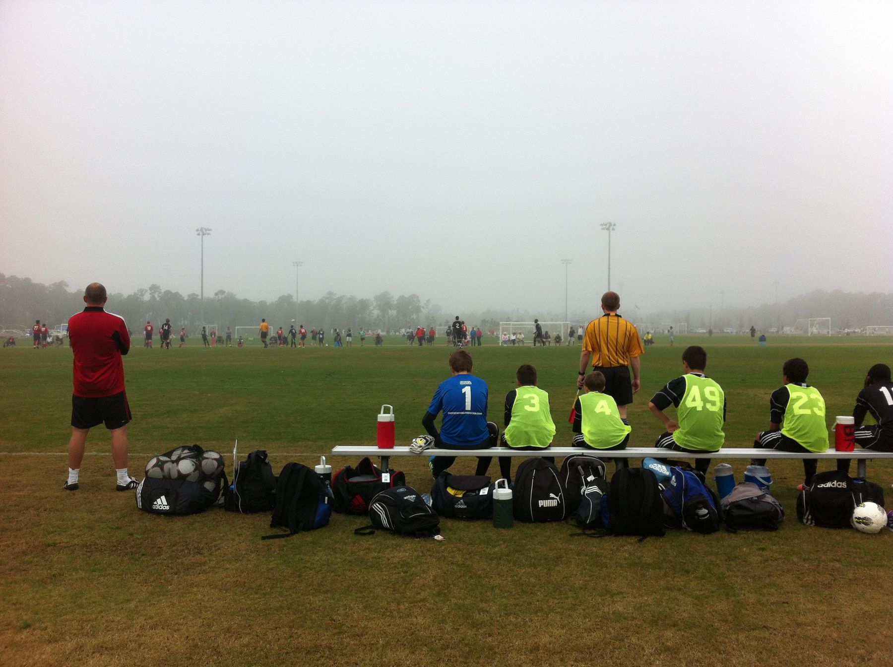 A coach and substitutes watching from the bench