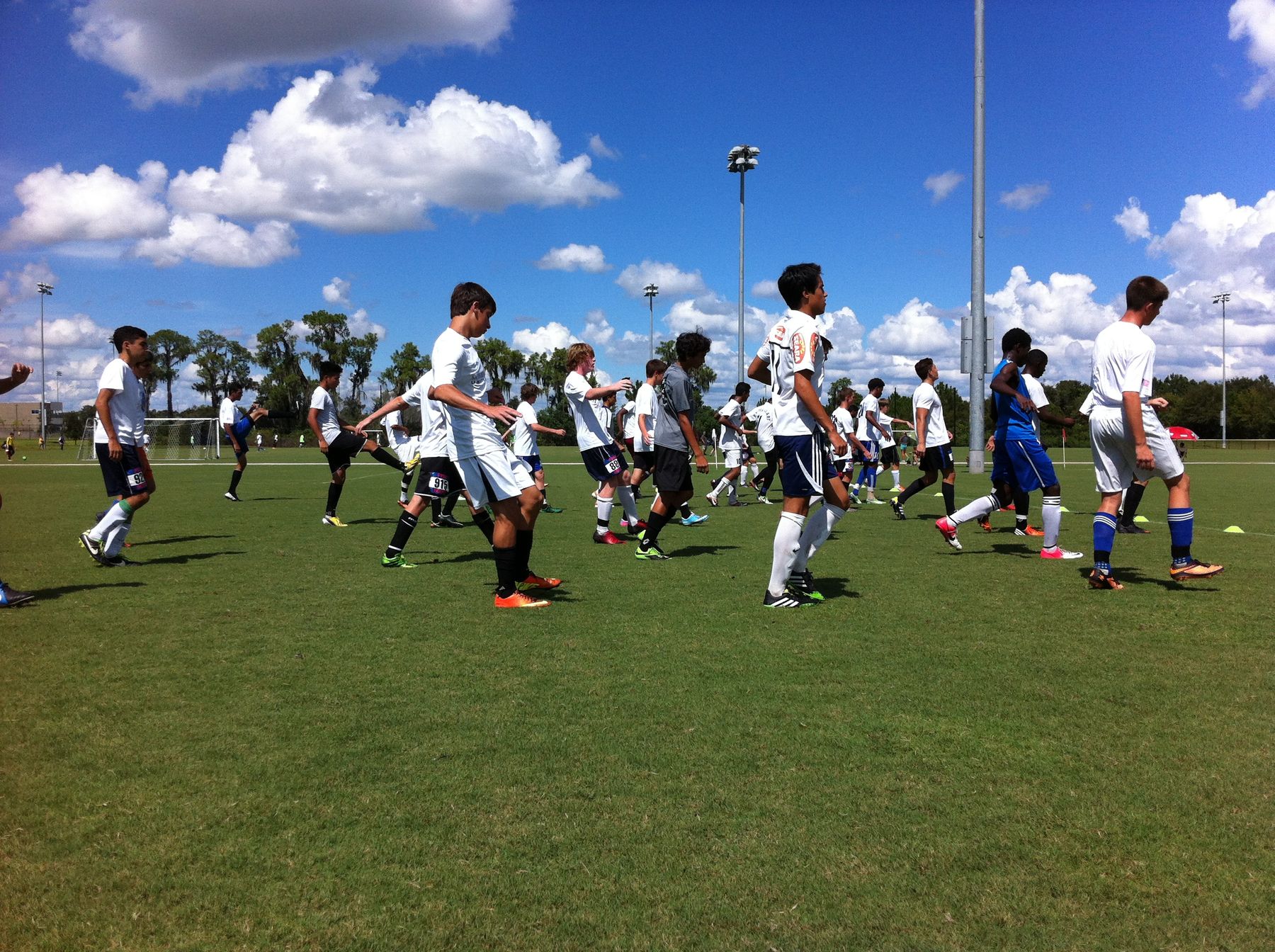 A large group of players warming up under a blue sky